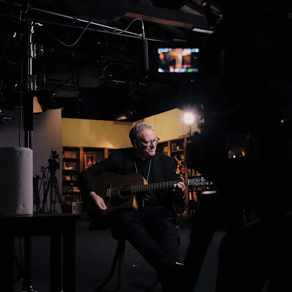 Bishop Barron playing guitar on Meaning of Music film series